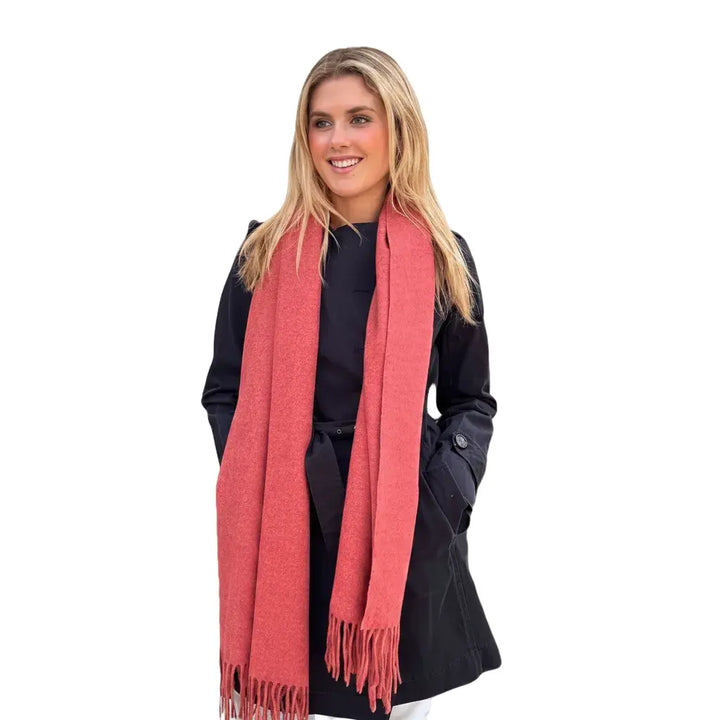 Woman wearing a pink scarf and black coat on a light gray background
