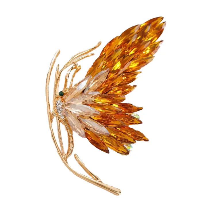 Decorative brooch with amber-colored feathers on a white background