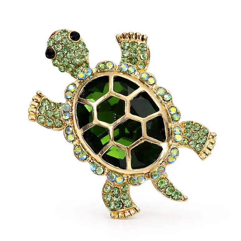 Decorative turtle brooch with green gemstones on a white background