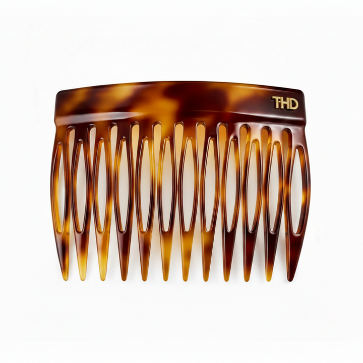 A tortoiseshell hair comb with a glossy amber and brown pattern, featuring a gold THD logo on the top right, set against a plain white background.