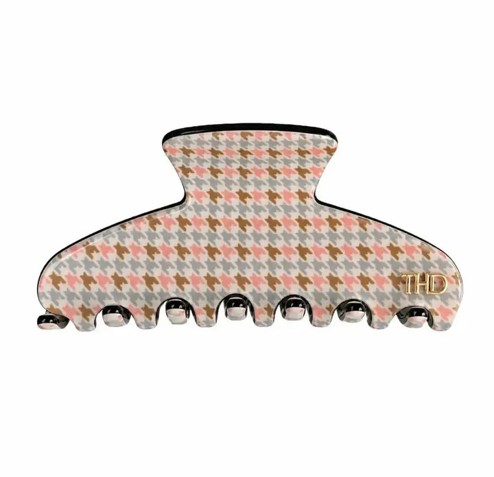 A large hair claw clip featuring a pastel houndstooth pattern with pink, brown, and gray colors on a white base, with a small gold 'THD' logo on the right side.